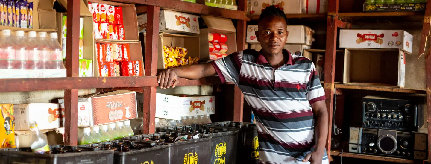 Un hombre posando frente a su negocio en Mozambique